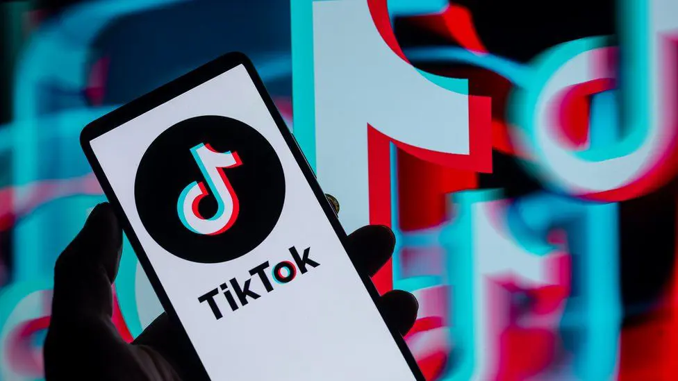 TikTok отображается на смартфоне со значком TikTok на заднем плане.