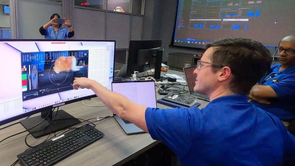 Сотрудники НАСА указывают на видео с котом на экранах своих компьютеров