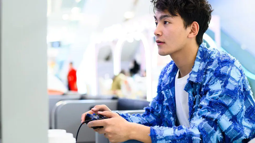 Мужчина азиатского происхождения играет в видеоигру