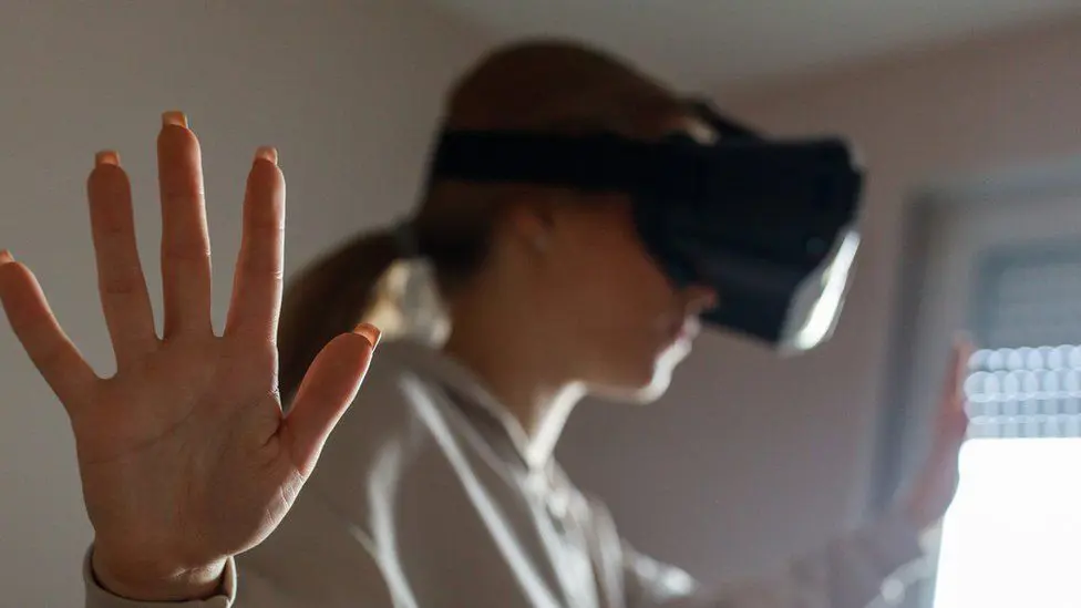 Стандартное размытое изображение девушки, использующей гарнитуру виртуальной реальности.