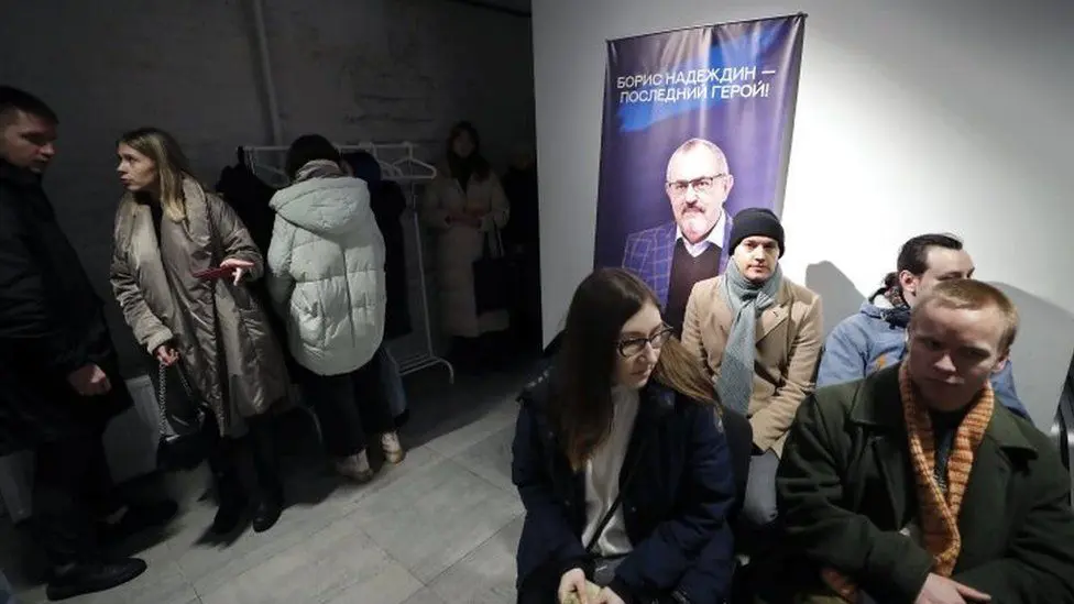 Люди стоят в очереди, чтобы поставить подписи под кандидатурой Надеждина - плакат на заднем плане описывает его как «последнего героя».