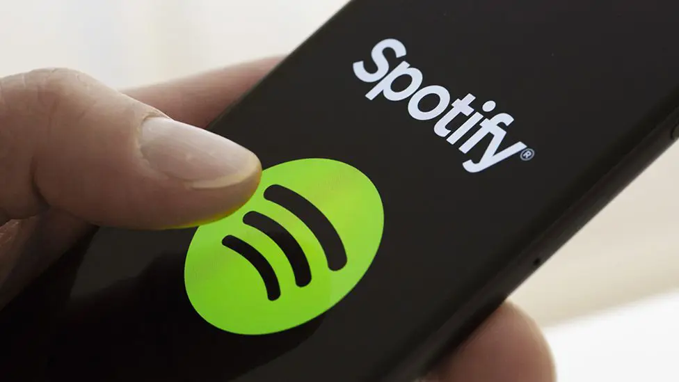Логотип Spotify виден на смартфоне, когда кто-то им пользуется