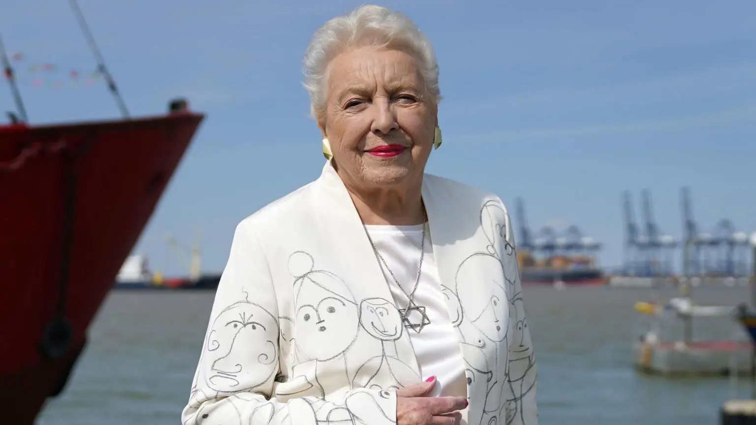 Стойкая, умная и опережающая своё время — как дама Стефани изменила роль женщин в технологической индустрии 1 Дама Стефани Ширли позирует на фоне моря в белом костюме, расписанном рисунками детей, и с ожерельем со звездой Давида на открытии мемориала организации «Киндертранспорт» на набережной в Харвиче в 2022 году