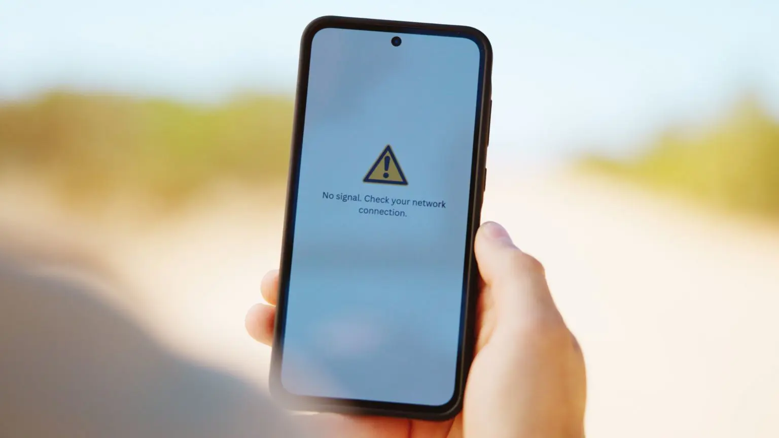 Анонсированы первые в Великобритании телефоны, которые получат спутниковое подключение в зонах с низким уровнем сигнала 1 Человек держит телефон на простом белом фоне. На экране отображается сообщение об ошибке, указывающее на отсутствие сигнала.