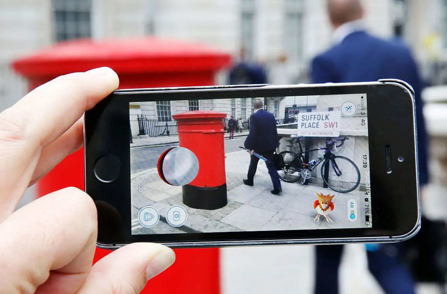 10 лет Pokémon Go, и миллионы всё ещё пытаются поймать их всех. 5 Телефон, расположенный горизонтально, с запущенной игрой Pokémon Go, наведённой на адрес в Великобритании: Suffolk Place. В углу телефона сидит покемон Спироу.